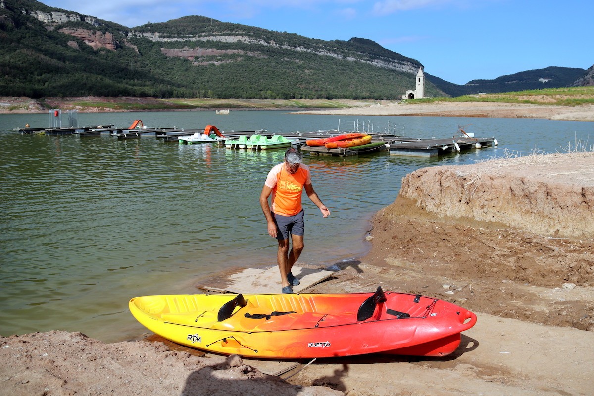 Un treballador posa un caiac al pantà de Sau, visiblement afectat per la sequera - ACN Un treballador posa un caiac al pantà de Sau, visiblement afectat per la sequera - ACN