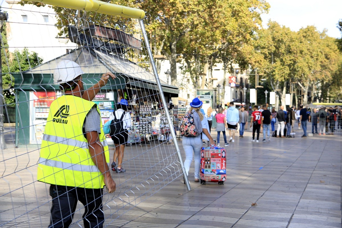 Un obrer col·loca una tanca a la Rambla mentre passegen els turistes - ACN