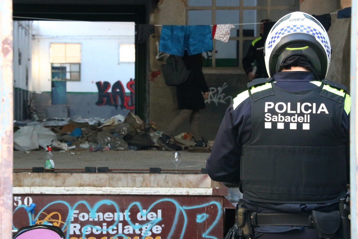 Pla mitjà d'un agent d'esquena dins la nau ocupada que la Policia Municipal de Sabadell - ACN