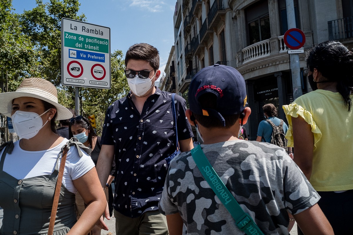 Gent amb mascareta al centre de Barcelona, aquest divendres, després que el Govern hagi recomenat quedar-se a casa als ciutadans de l'àrea metropolitana. - Adrià Costa