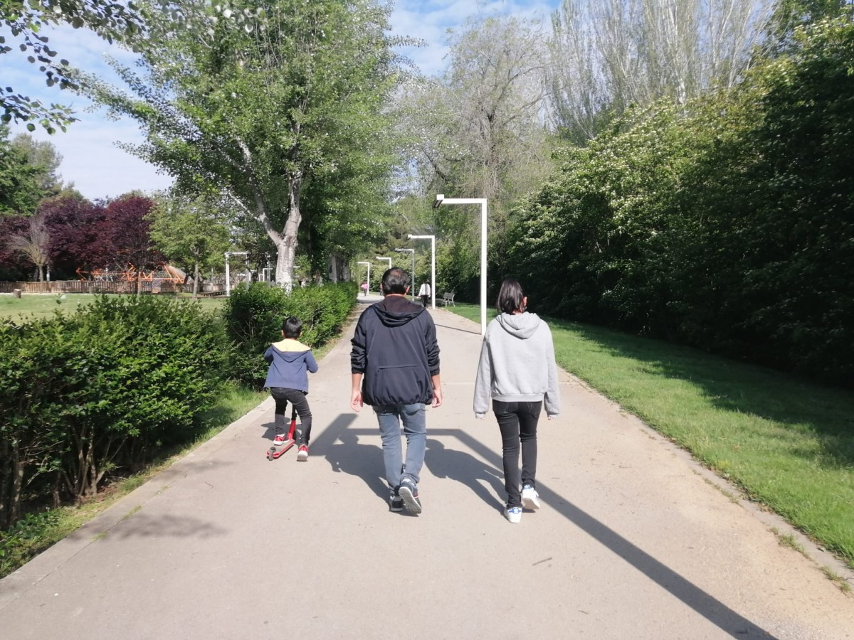 Un pare acompanyat dels seus dos fills passejant per un parc de la ciutat - Sergi Baixas