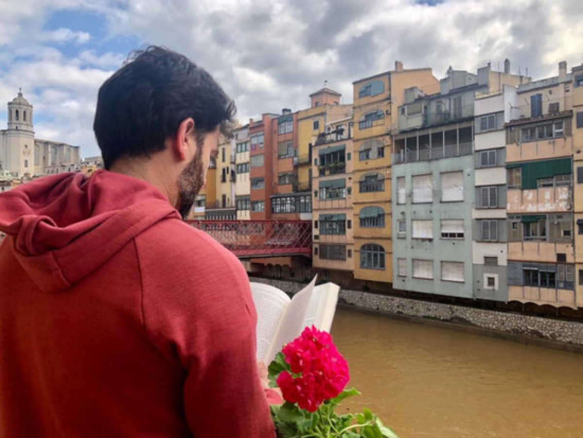 Un jove llegint des del seu balcó a Girona.  - ACN 