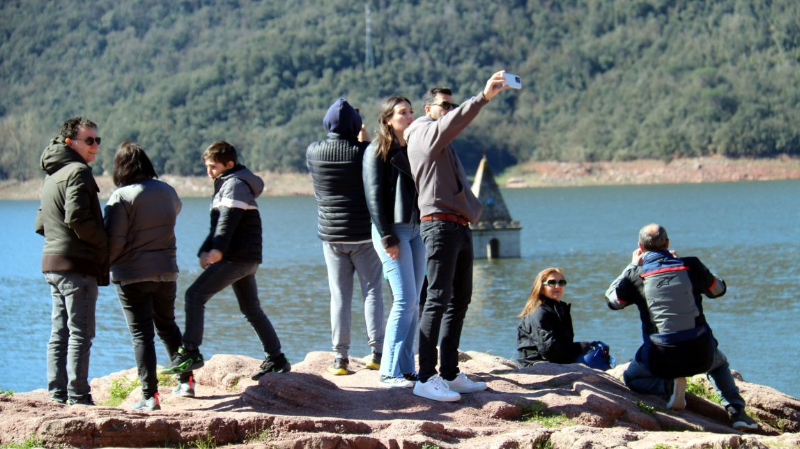 Un grup de turistes fotografiant-se amb el campanar de Sau aquest diumenge al matí                                                                             |                                ACN - |                                ACN