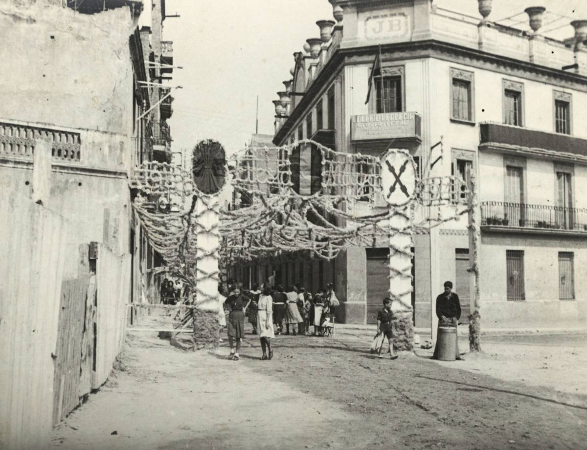 Guarnit del Carrer d’Alcolea amb el Passeig de Sant Antoni amb símbols franquistes i carlistes (1941) - Arxiu Municipal De Sants-Montjuïc Guarnit del Carrer d’Alcolea amb el Passeig de Sant Antoni amb símbols franquistes i carlistes (1941)