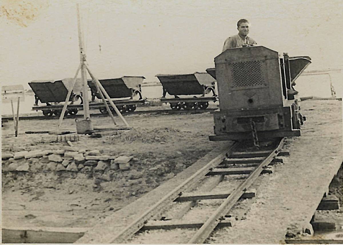 Un treballador assegut a sobre d`una locomotora amb les vagonetes carregades de sal
