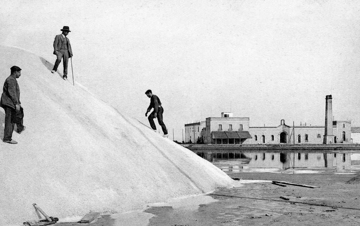 Treballadors a sobre la garbera, amb l`edifici central de la salinera de fons