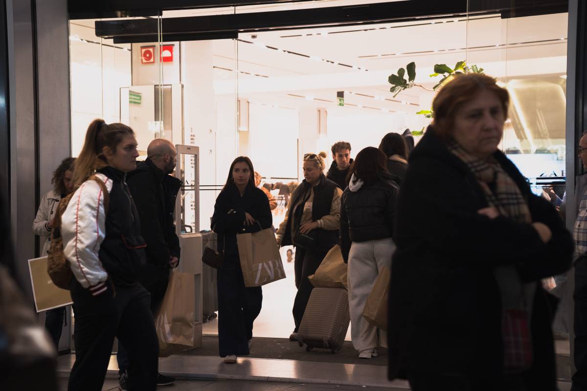 Un grup de gent amb bosses a la sortida d`una botiga d`Inditex