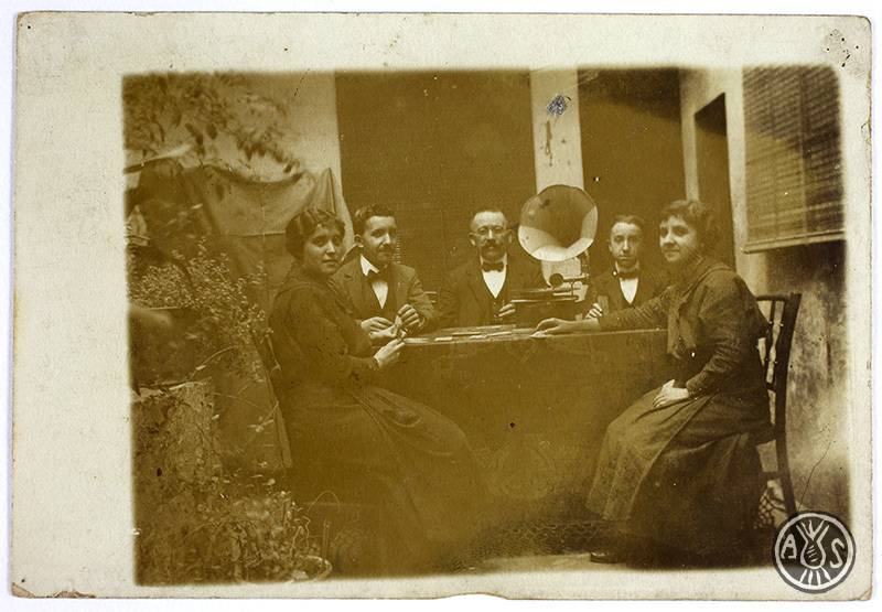  Dones i homes al voltant d'una taula, el 1910 - Desconegut (AHS)