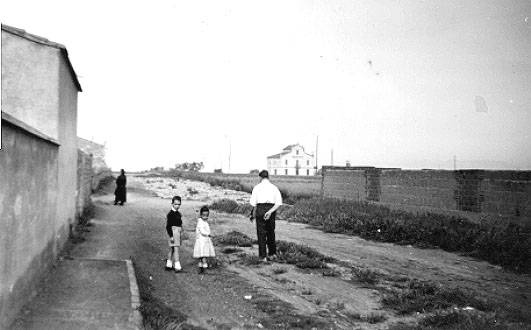 1950. Carrer Pérez Moya. A l’esquerra, el mur i la vorera de l’escola. Al centre, dos alumnes. - El nen esdevindrà el director de l’escola de la tercera generació, és 