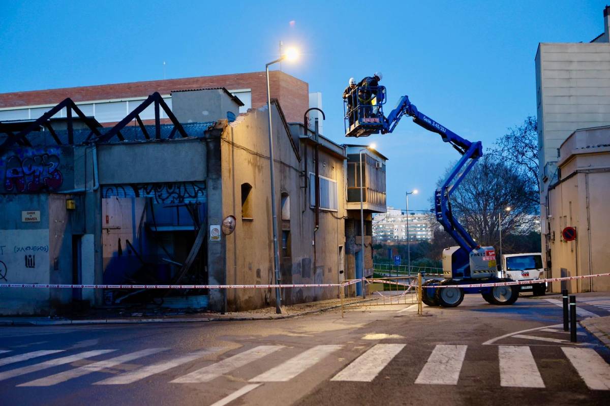 Operaris fent tasques de revisió de la façana de la nau industrial hores després del succés