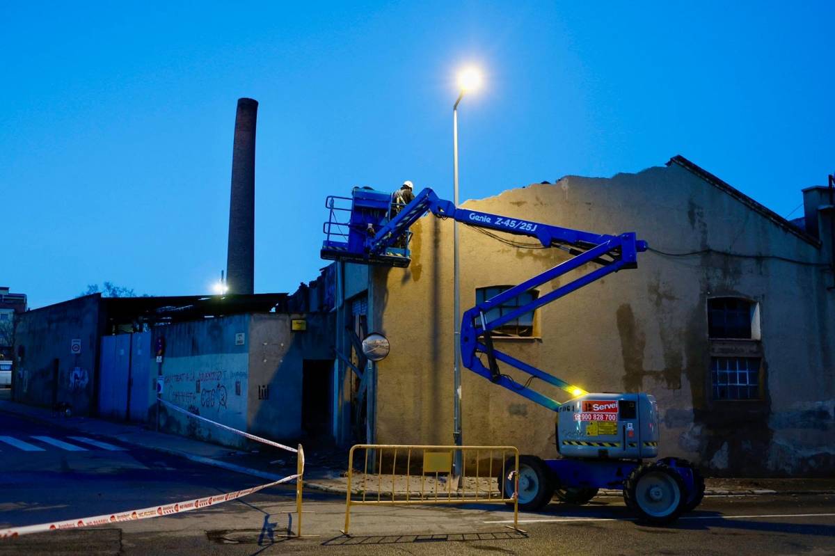 Operaris fent tasques de revisió de la façana de la nau industrial hores després del succés