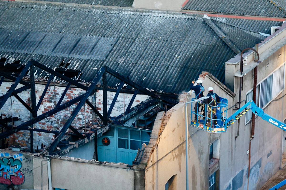 Operaris fent tasques de revisió de la façana de la nau industrial hores després del succés