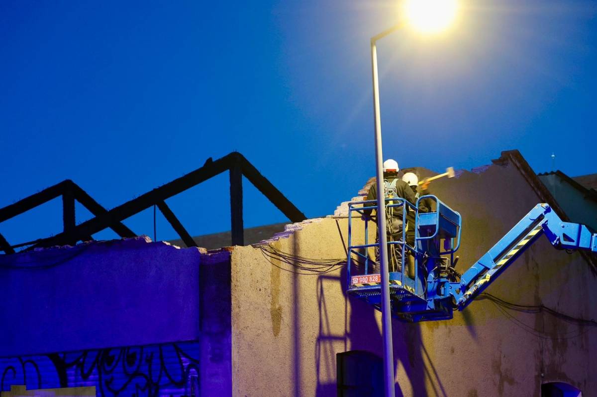 Operaris fent tasques de revisió de la façana de la nau industrial hores després del succés