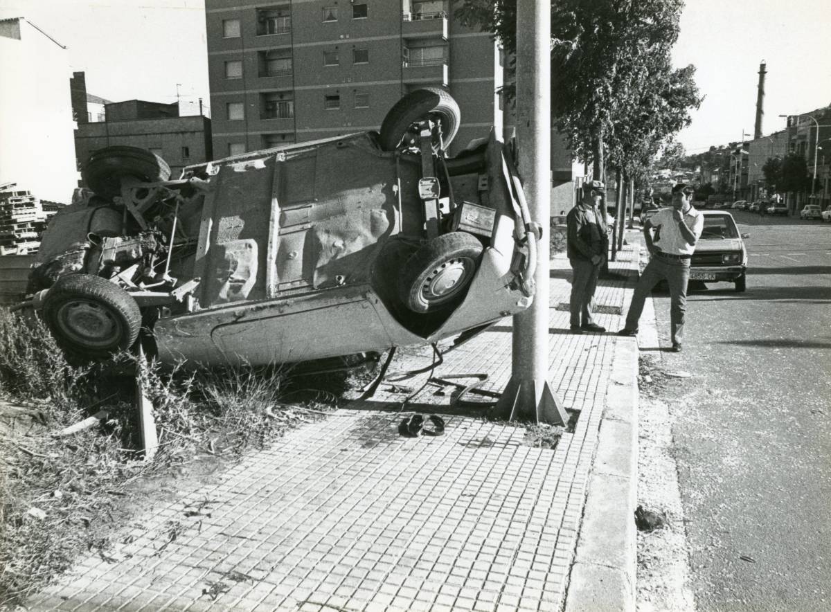 Un cotxe bolcat i la xemeneia al fons