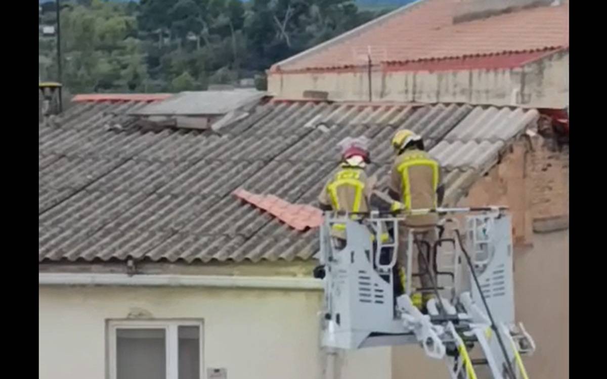 Els Bombers retiren una peça de teulada desplaçada pel vent en un edifici del carrer Magnet