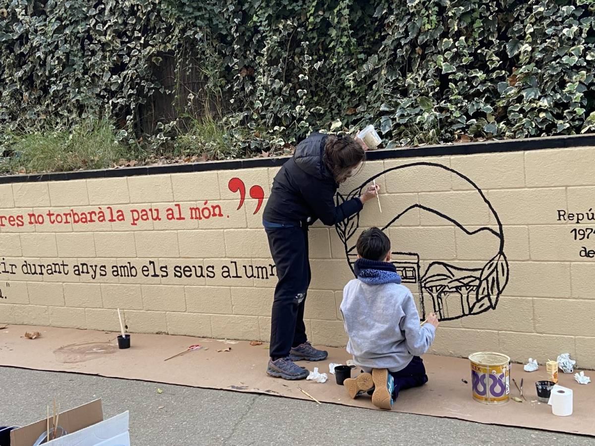 Una mare i un fill pintant el mural a l'entrada de l'escola. - AFA Pallerola