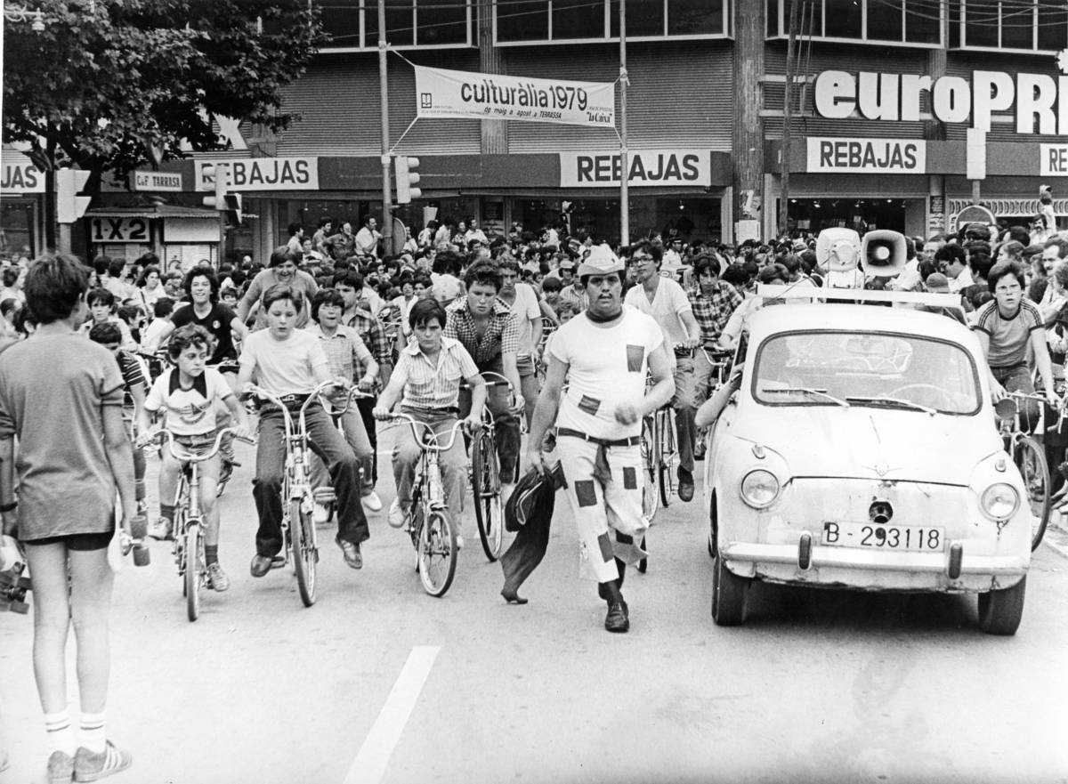 El Cantinflas terrassenc, enmig d’uns joves ciclistes al portal de Sant Roc  - ARXIU DIARI DE TERRASSA