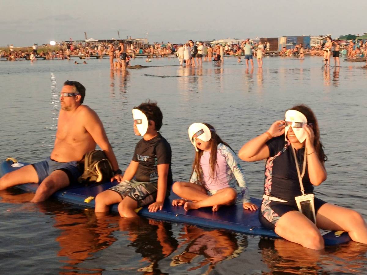 Una família gaudeix de l'espectacle de l'eclipsi amb els peus a l'aigua.  -  Quim Giró