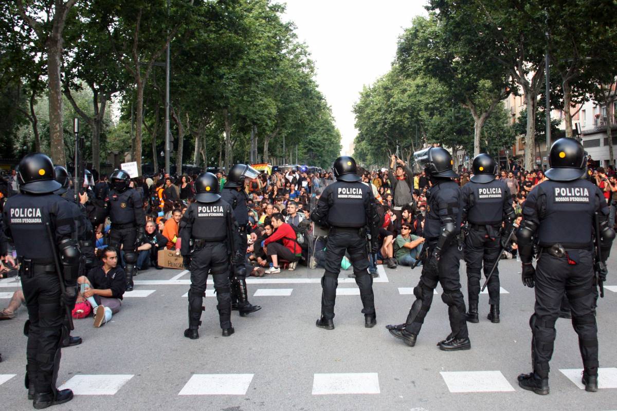Manifestants asseguts a terra davant del desplegament policial  davant les portes del Parc de la Ciutadella. - ACN